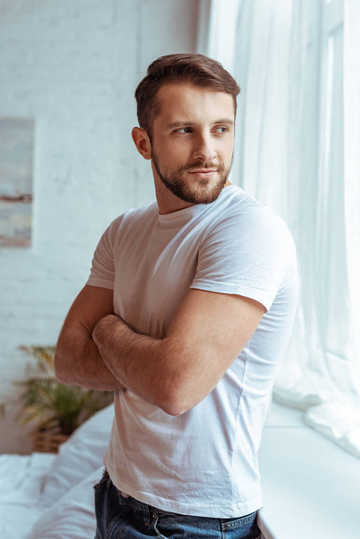 handsome man with crossed arms in white t-shirt looking away  - Фото, изображение