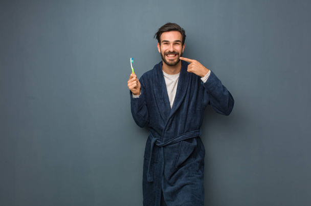 Fiatal férfi pizsama holding egy teethbrush visel - Fotó, kép