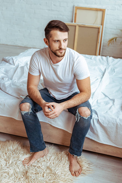good-looking man in white t-shirt and jeans looking away  - Foto, Imagen