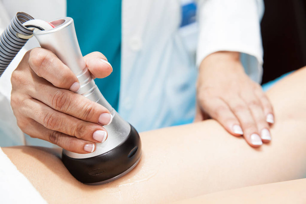 Doctor performing an ultracavitation treatment on a young female patient leg - Photo, Image