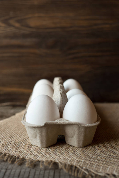 Raw eggs in egg box on wooden background. - Фото, изображение