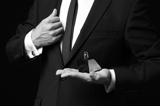 Hombre guapo con botella de perfume sobre fondo oscuro, primer plano
 - Foto, imagen