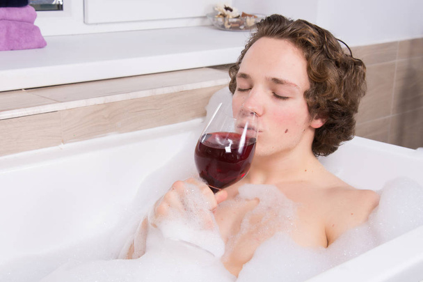 Sexy guy and red wine. Bath. - 写真・画像