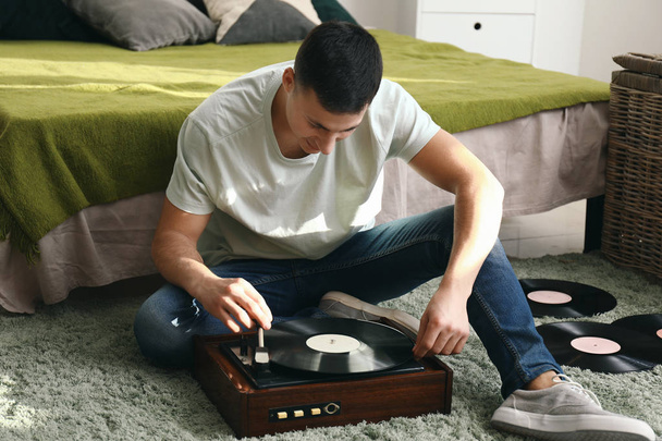 Young man listening to music on record player at home - Fotografie, Obrázek