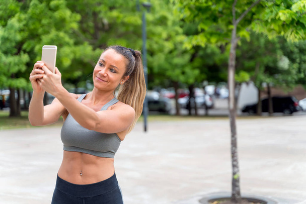 An athletic woman taking a selfie in the park - Foto, afbeelding