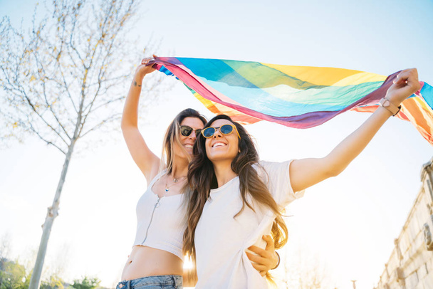 路上でゲイプライドフラグを持つカップルレズビアンの女性 - 写真・画像