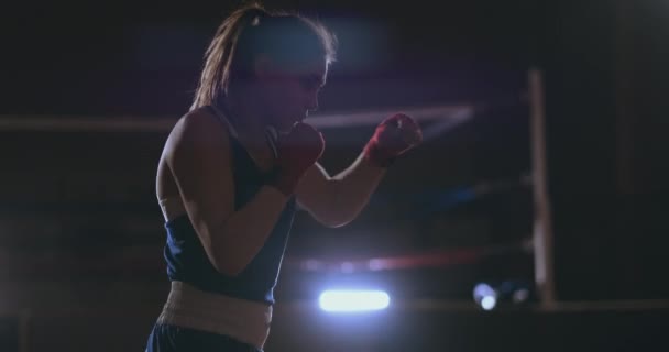 Allenamento boxer femminile in camera buia con retroilluminazione al rallentatore vista laterale. steadicam shot
 - Filmati, video