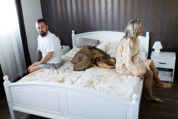 Couple having crisis in bed. Woman sitting on bed's edge. - Фото, зображення