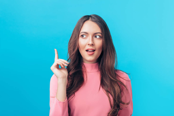 Young beautiful woman having good idea with her finger pointing up, blue background. Success, idea and innovation concept. - Foto, imagen