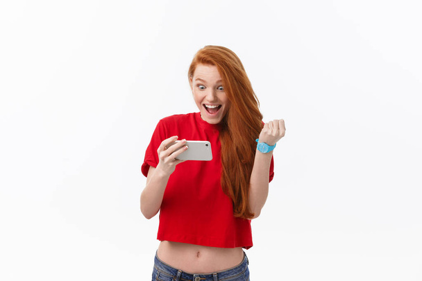 Photo of emotional young caucasian woman play games by phone. Looking aside - Photo, Image