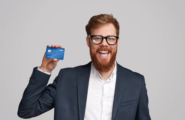 Homem de gengibre alegre apresentando cartão bancário
 - Foto, Imagem
