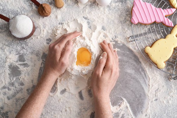 Vrouw maken deeg voor Pasen koekjes aan tafel - Foto, afbeelding