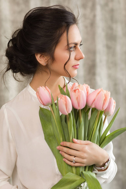 beautiful brunette woman with a bouquet of tulips flowers - Foto, imagen