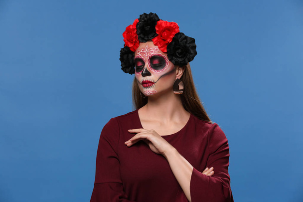 Jeune femme avec crâne peint sur son visage pour la fête des morts du Mexique sur fond de couleur - Photo, image