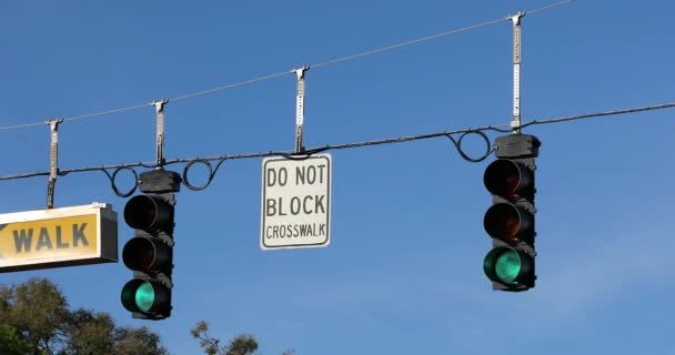 Δύο πράσινα φώτα κυκλοφορίας και πινακίδες δρόμου κρέμονται σε ένα καλώδιο πάνω από το δρόμο εναντίον του γαλάζιου ουρανού για διεθνή οδήγηση στο Ορλάντο, Φλόριντα, Ηνωμένες Πολιτείες-DCI 4K ψήφισμα - Πλάνα, βίντεο
