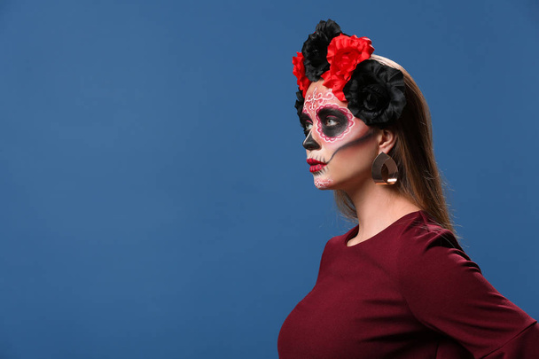 Young woman with painted skull on her face for Mexico's Day of the Dead against color background - Photo, Image