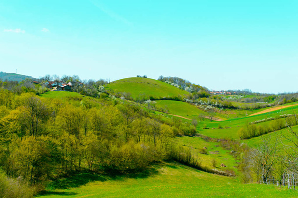 丘の上に小さな農場。ヨーロッパの春に谷や丘。美しい風景. - 写真・画像