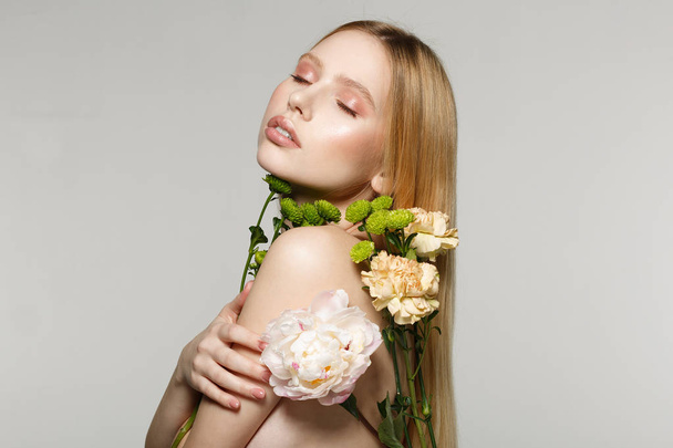 Side view portrait of charming young blonde girl with perfect makeup and closed eyes, pressed flowers to her body - Φωτογραφία, εικόνα