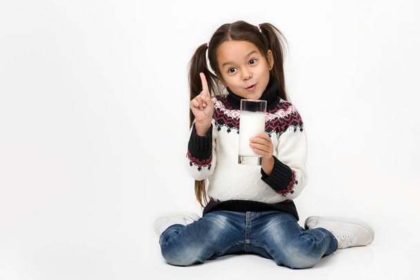little child girl holding glass of milk on white background - Foto, afbeelding