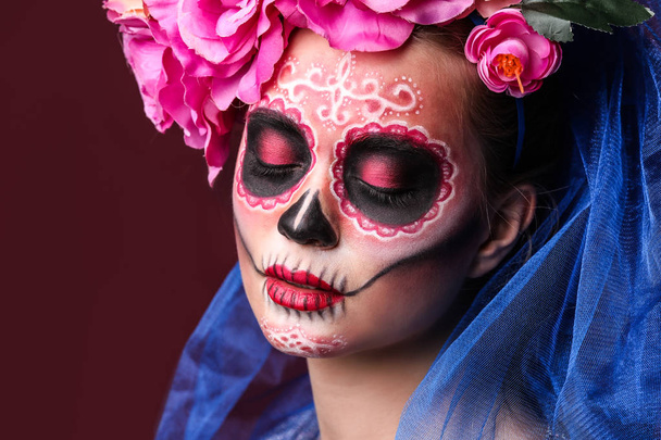 Young woman with painted skull on her face for Mexico's Day of the Dead against color background - Photo, Image