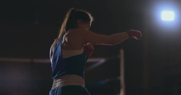 eine schöne Frau führt einen Schattenkampf und übt Technik und Schlaggeschwindigkeit, während sie hart für zukünftige Siege trainiert. dunkler Sporthintergrund. Steadicam-Aufnahme - Filmmaterial, Video