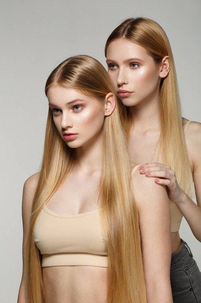 Kaksi seksikäs houkutteleva kaksoset nainen vaaleat pitkät hiukset poseeraa glamouria meikki
 - Valokuva, kuva