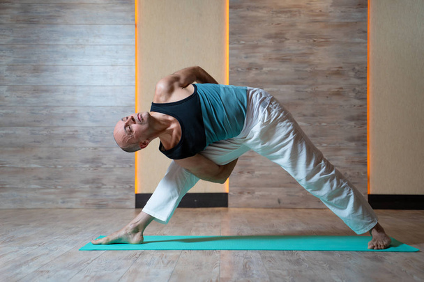 Sportive man looking up doing yoga on blue mat. - Photo, Image