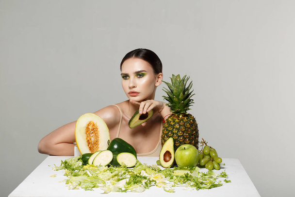 Horizontal portrait of european woman with half of avocado in hand - Fotó, kép
