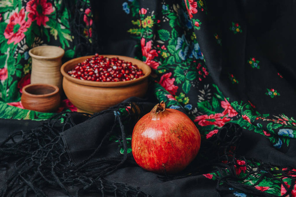 pomegranate grains in a ceramic bowl on a vintage fabric background, pomegranate fruit, ceramic jug, ceramic plate, ethnic shawl, Romma shawl, still life - Fotoğraf, Görsel