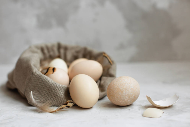 Huevos de Pascua en una bolsa de lona sobre un fondo gris
. - Foto, Imagen