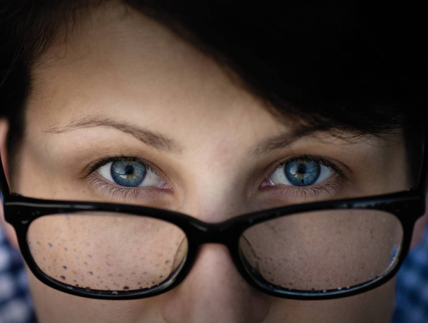 Κορίτσι με πρόβλημα όρασης, φαίνεται μέσα από τα γυαλιά. Γυαλιά που καλύπτεται με σταγόνες του νερού (βροχή). - Φωτογραφία, εικόνα