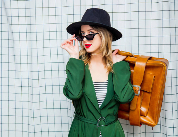 woman in hat and green cloak in 90s style with travel suitcase  - Photo, Image