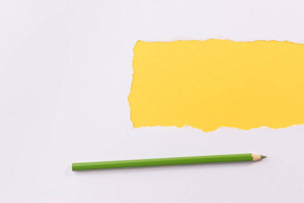 White torn paper over yellow background with pencil - Valokuva, kuva