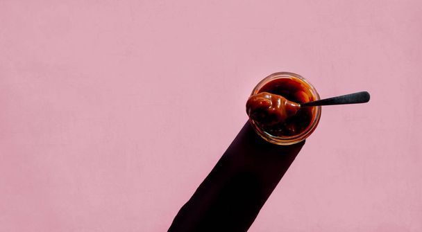 Karamel flesje met lepel en lange schaduw. Boven weergave  - Foto, afbeelding