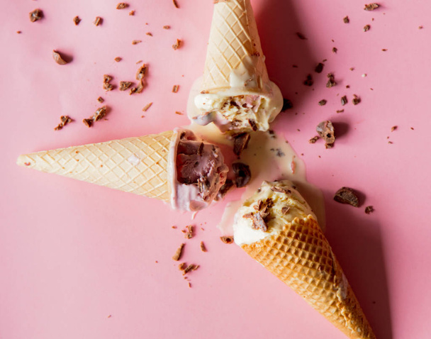 broken and spilled cream and chocolate ice-cream on pink background. Above view  - Foto, Imagen