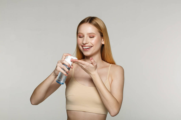 Pretty young blonde girl with perfect skin applying cosmetic cream on her hand - Foto, Imagem