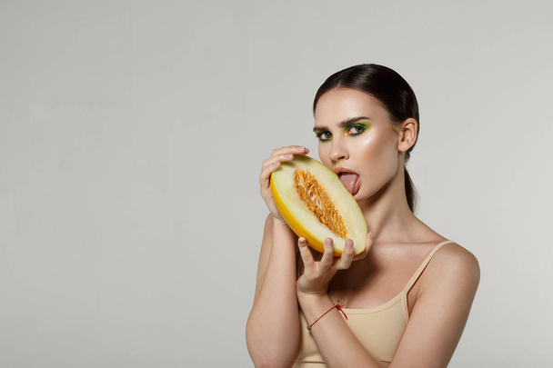 Linda morena sexy modelo femenino lamiendo un melón en rodajas
 - Foto, Imagen