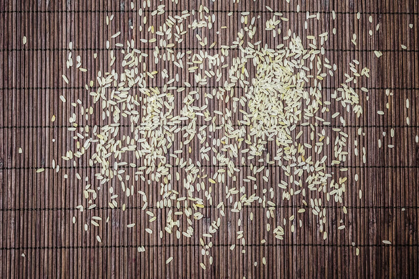 white rice on brown bamboo background. organic rice on natural background. flat lay,  top view.  - 写真・画像