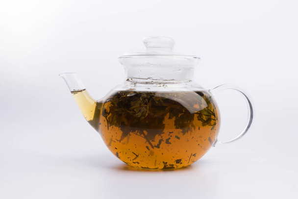 Herbal tea in a teapot with fresh herbs isolated on white background - Фото, изображение