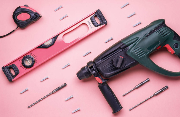 Flat layout: perforator and other hand tools for construction and repair on a pink background. - Fotó, kép