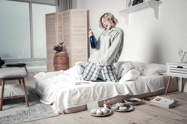 Frau trinkt nach Trennung Alkohol und isst im Schlafzimmer - Foto, Bild