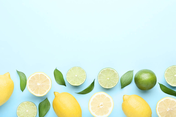 Rijpe citroenen en limoenen (lemmetjes) met groene blaadjes op blauwe achtergrond - Foto, afbeelding
