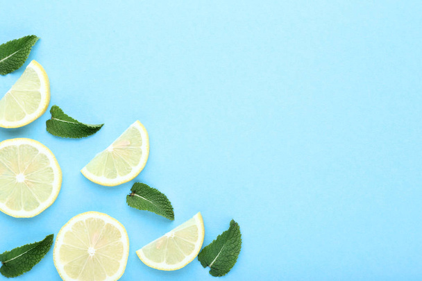 Pieces of lemons with green leafs on blue background - Foto, afbeelding