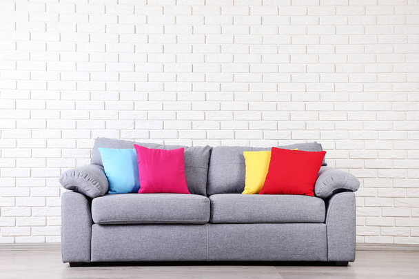 Modern grey sofa with colorful pillows on brick wall background - Foto, Imagem