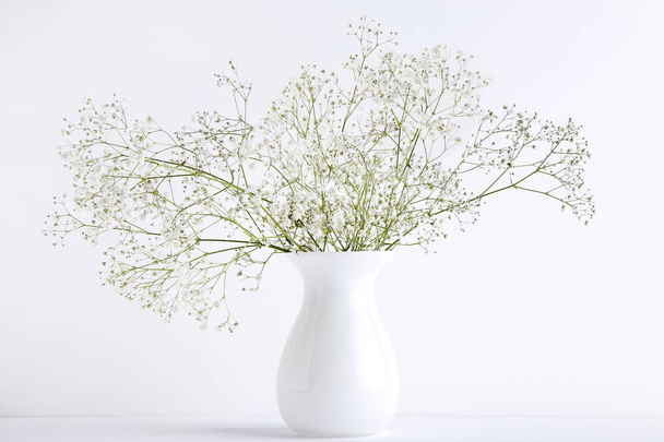 White gypsophila flowers in vase on grey background - Foto, Imagen