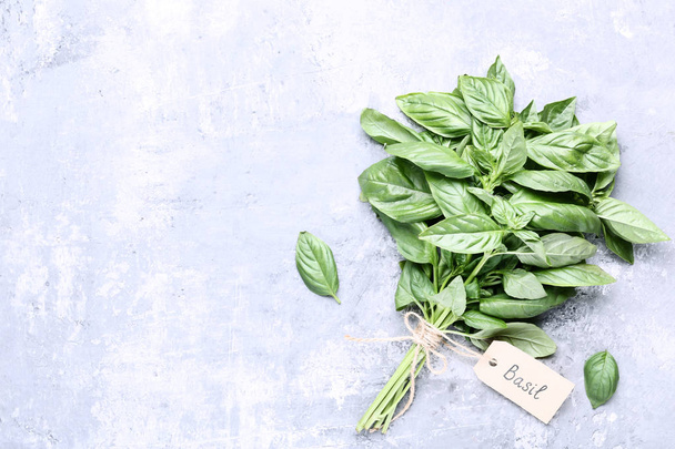 Green basil leafs with paper card on grey wooden table - Foto, imagen