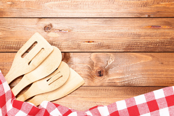 Wooden cutlery with red napkin on brown table - Фото, зображення