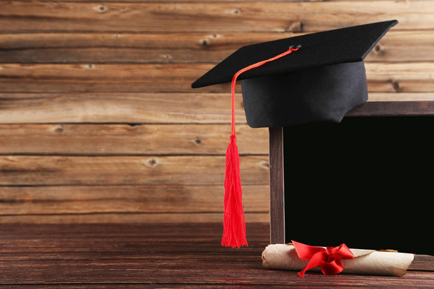Graduation cap with diploma and blank frame on brown wooden tabl - Φωτογραφία, εικόνα