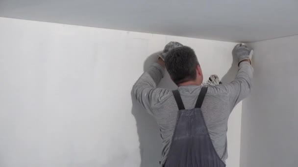 człowiek malarza Miele ścianę. Handyman wyrównuje ściany z papierem piaskim - Materiał filmowy, wideo
