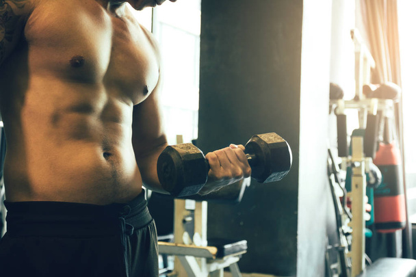 Asian sportsman raise dumbbell with muscular building at gym. - Fotó, kép